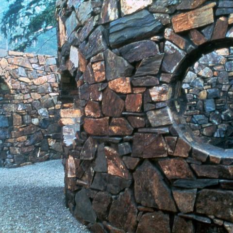 View of circular paneless windows and an archway of Nancy Holt's sculpture Stone Enclosure: Rock Rings. Full description in body text.