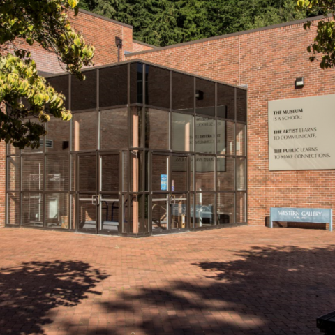 brick building and a brick plaza with a cube-shaped steel and glass atrium. The artwork hangs on the exterior brick wall to the right.