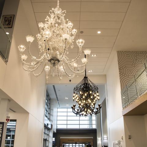 two chandelier sculptures hang above people inside the Viking Union common area