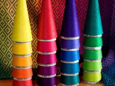 brightly colored cones of thread stacked in spectrum order