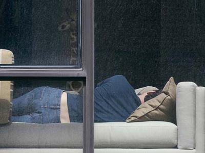 photo through a window of a guy laying on a sofa, back to the camera