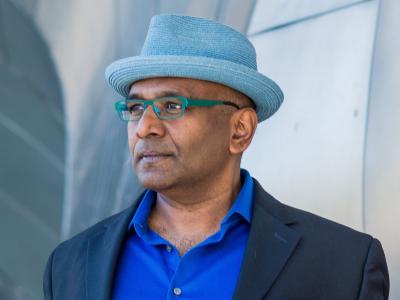 a man wearing glasses, a blue hat, blue collared shirt, and a blazer