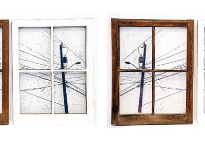four windows divided into four panes each. First and third window are bare wood frames, second and forth are white. Inside the panes is a painting or illustration of a utility pole with many wires extending form it.