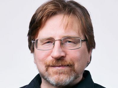 bearded fellow with straight brown hair, glasses, black collared shirt