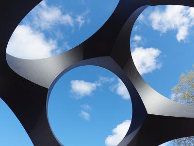 view of the blue sky with clouds through circular openings in a black geometry